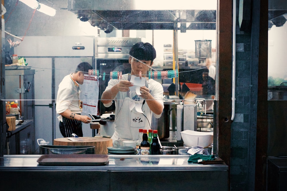 man in white shirt and white apron standing in front of counter