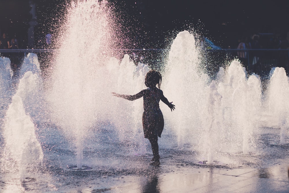 girl in black dress standing on water fountain