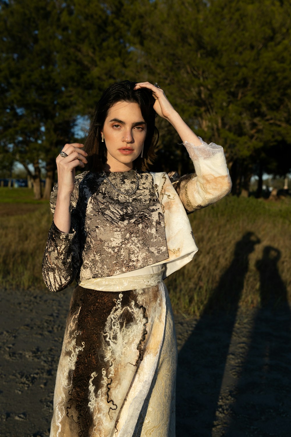 Femme en robe à fleurs noire et blanche debout sur un chemin de terre brun pendant la journée