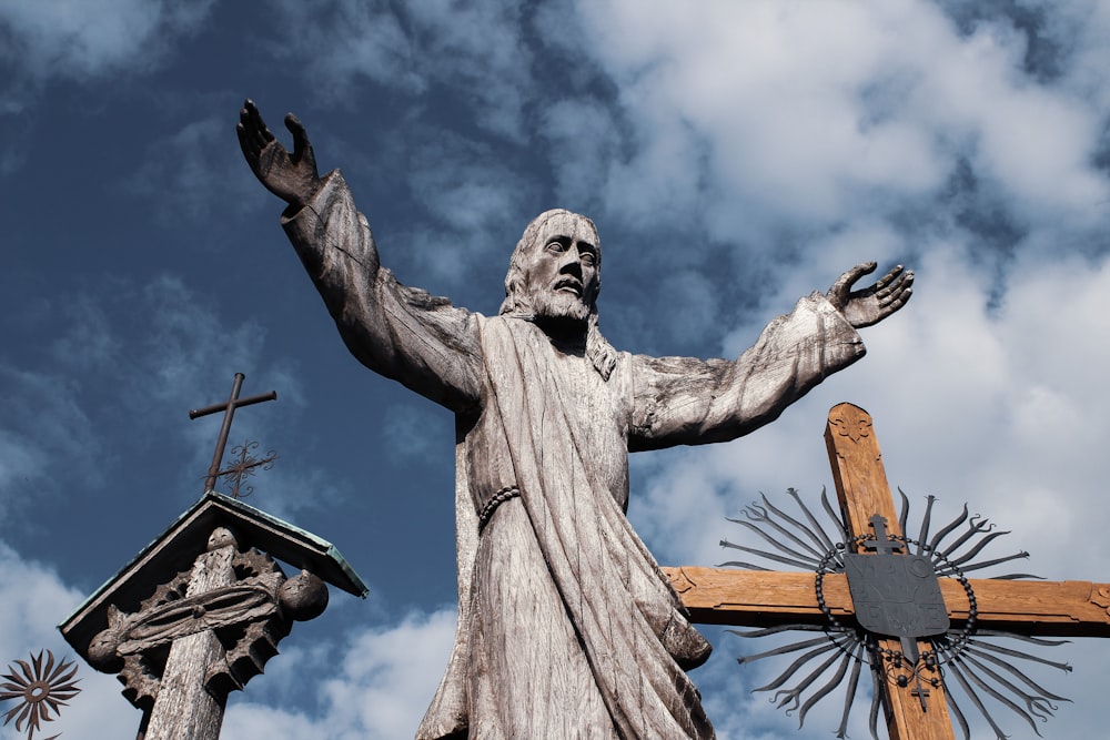 man holding cross statue under blue sky during daytime