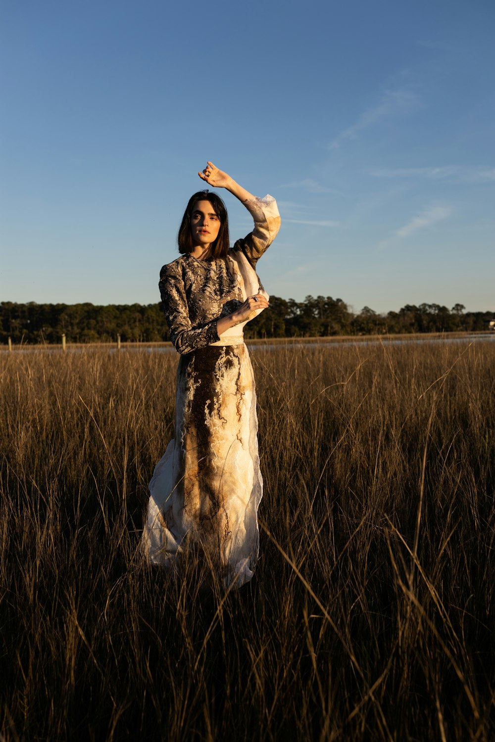 woman in brown and white dress standing on green grass field during daytime