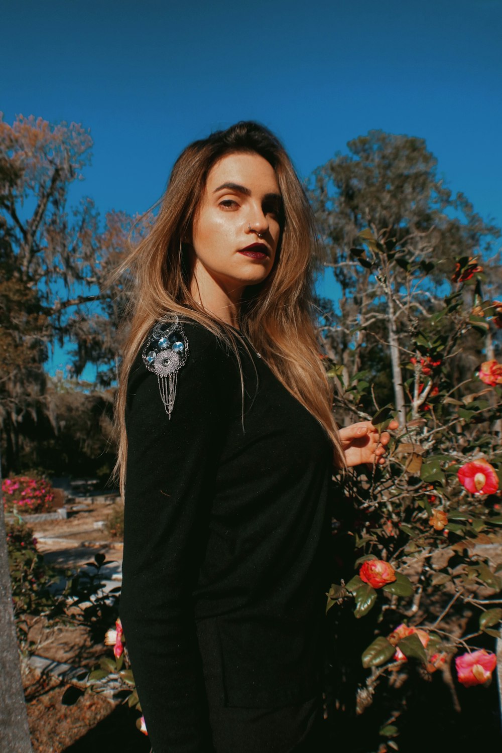 woman in black long sleeve shirt standing near red flowers during daytime