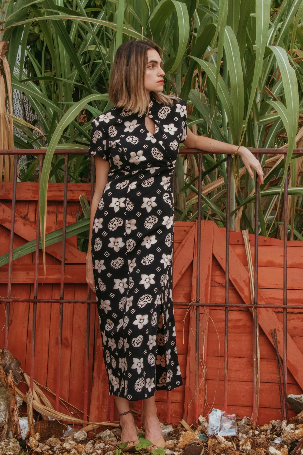 woman in black and white floral dress standing on brown wooden bridge during daytime