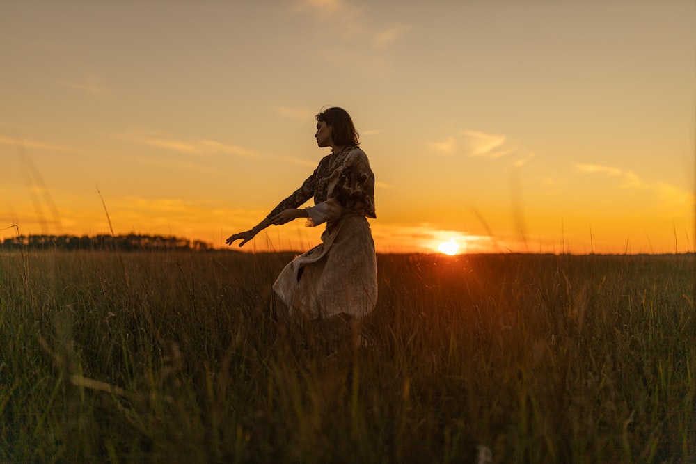 woman in white dress standing on green grass field during sunset