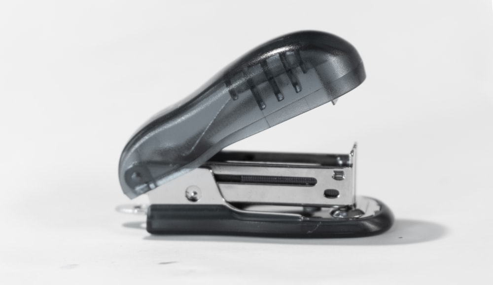 blue and silver stapler on white table