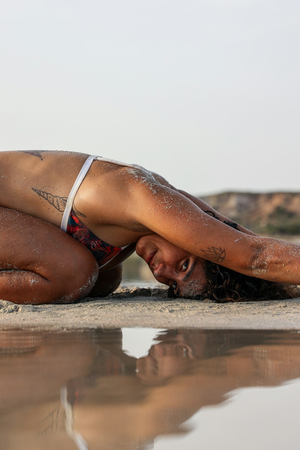 woman in white and black bikini lying on beach shore during daytime