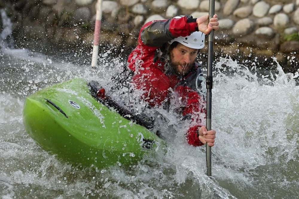man in red and white jacket riding green kayak