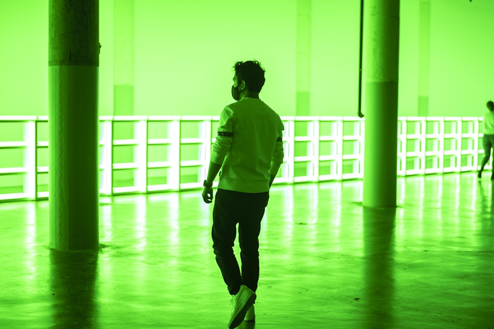 Mujer con camisa verde de manga larga y pantalones negros caminando por el pasillo