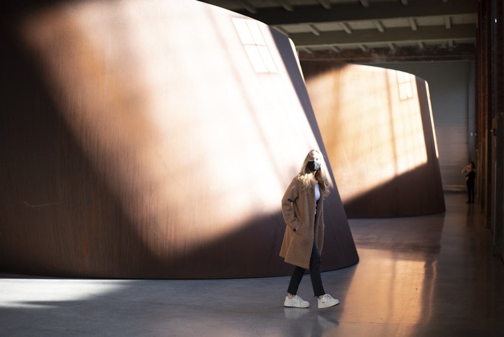 woman in brown coat standing on brown wooden floor
