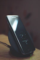 Smartwatch charging on a wireless dock with ambient lighting.