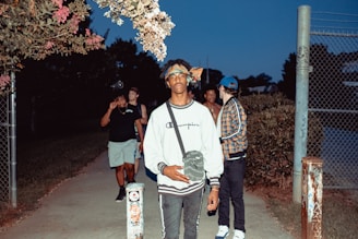 A diverse group of friends wearing punkyarn sweatshirts and t-shirts, hanging out on a city street corner at dusk.