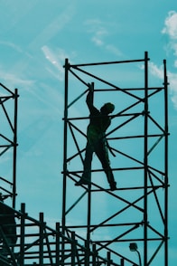 man in green t-shirt and green pants standing on black metal frame