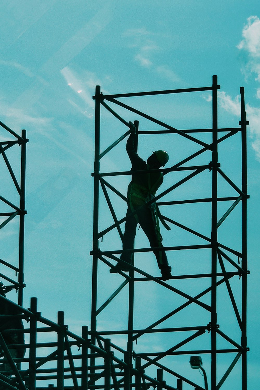 man in green t-shirt and green pants standing on black metal frame