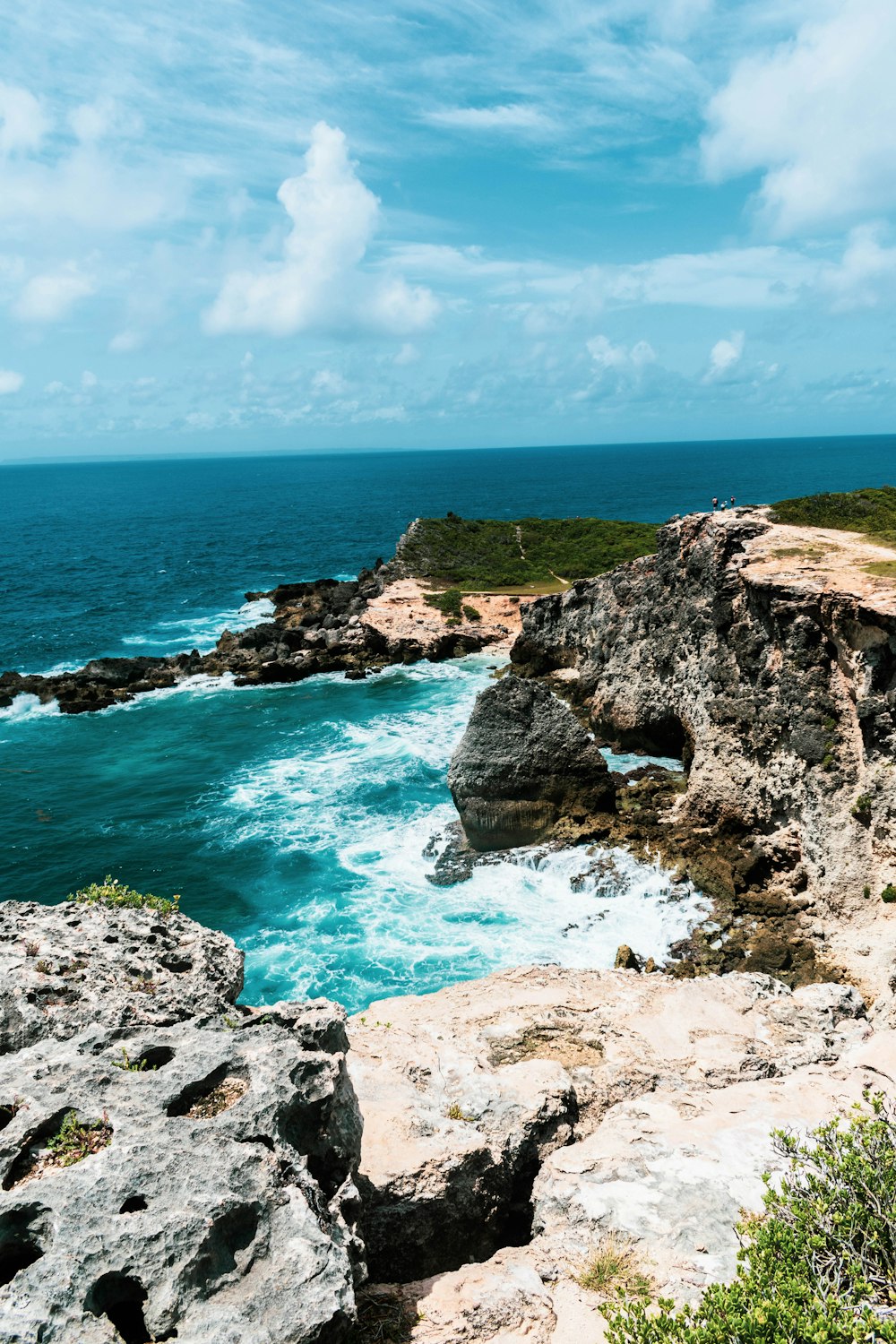 gray rock formation on sea under blue sky during daytime