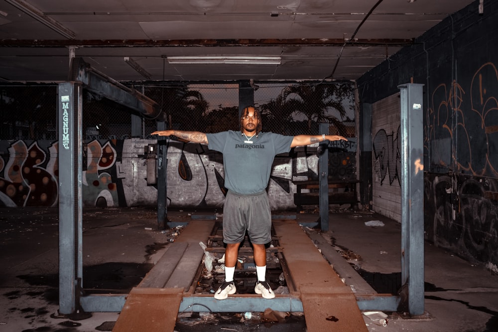 man in gray crew neck t-shirt and black shorts standing on brown wooden bench