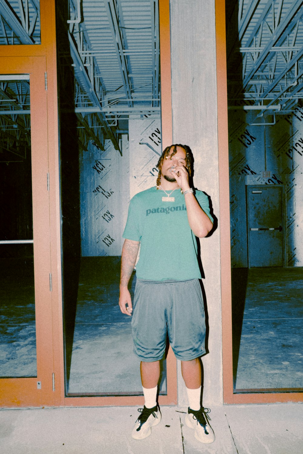 woman in gray crew neck t-shirt and blue denim shorts standing near brown wooden door