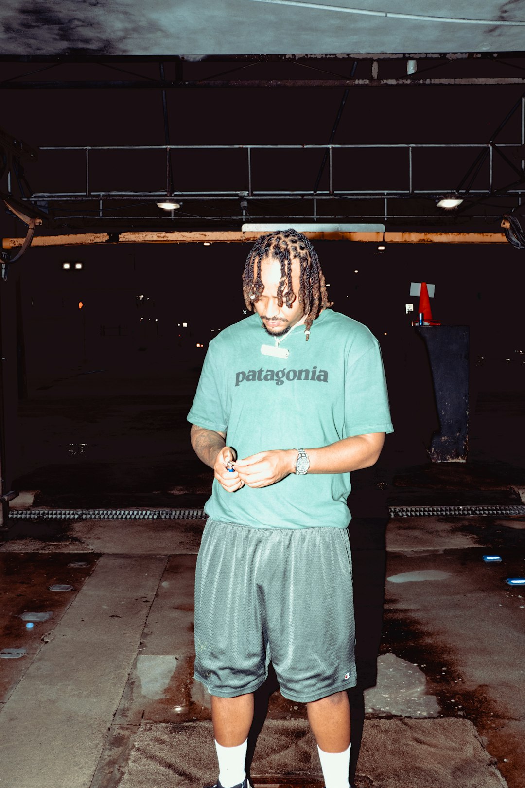 woman in green crew neck t-shirt and gray pants standing on street during nighttime