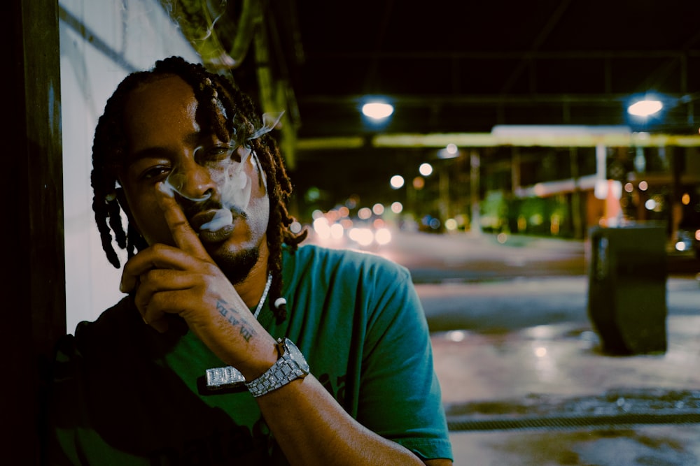 man in green crew neck t-shirt smoking cigarette