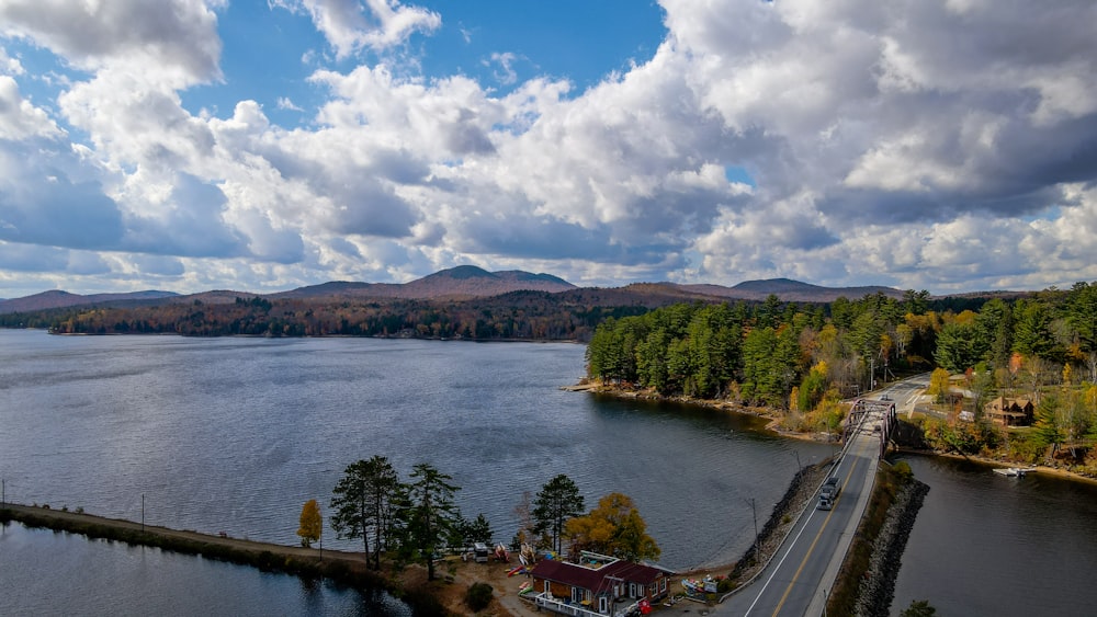 green trees near body of water under white clouds and blue sky during daytime