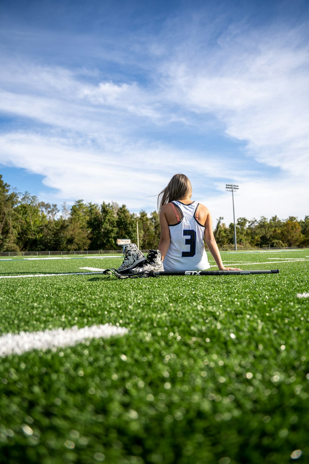 woman in white and black nike tank top sitting on green grass field during daytime