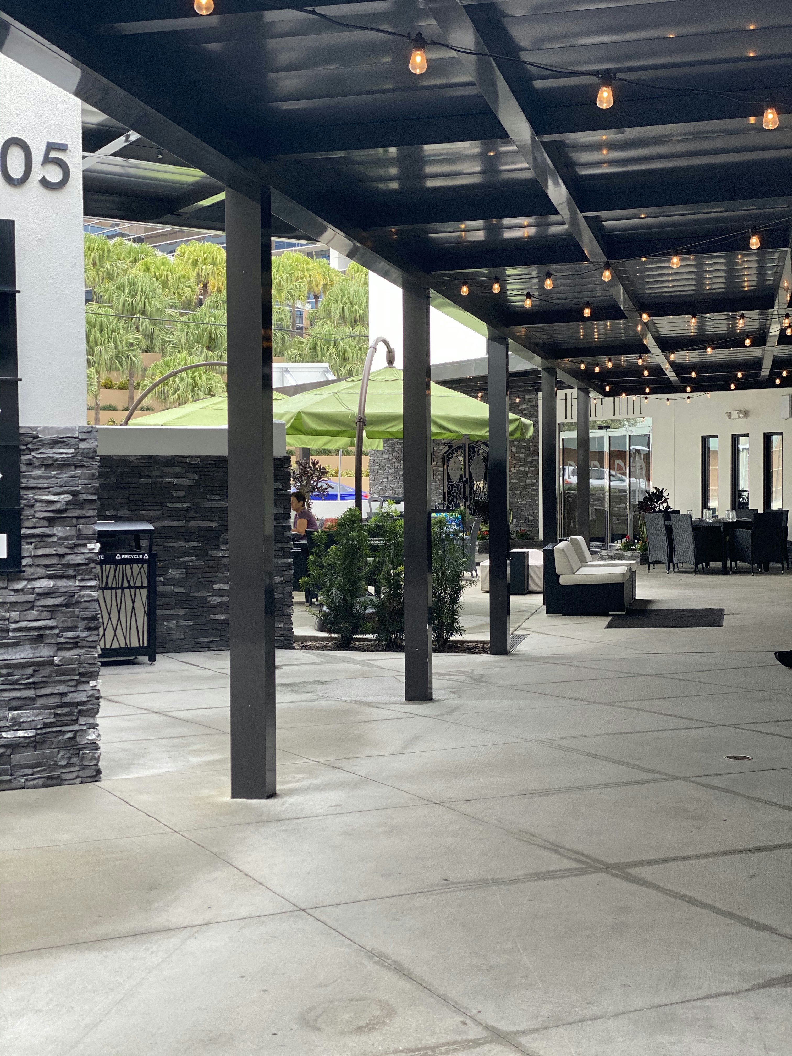 Outdoor patio seating with string lights and lush greenery in the evening