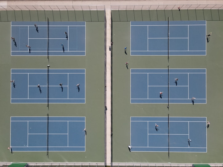 A group of diverse children playing tennis on a sunny court.