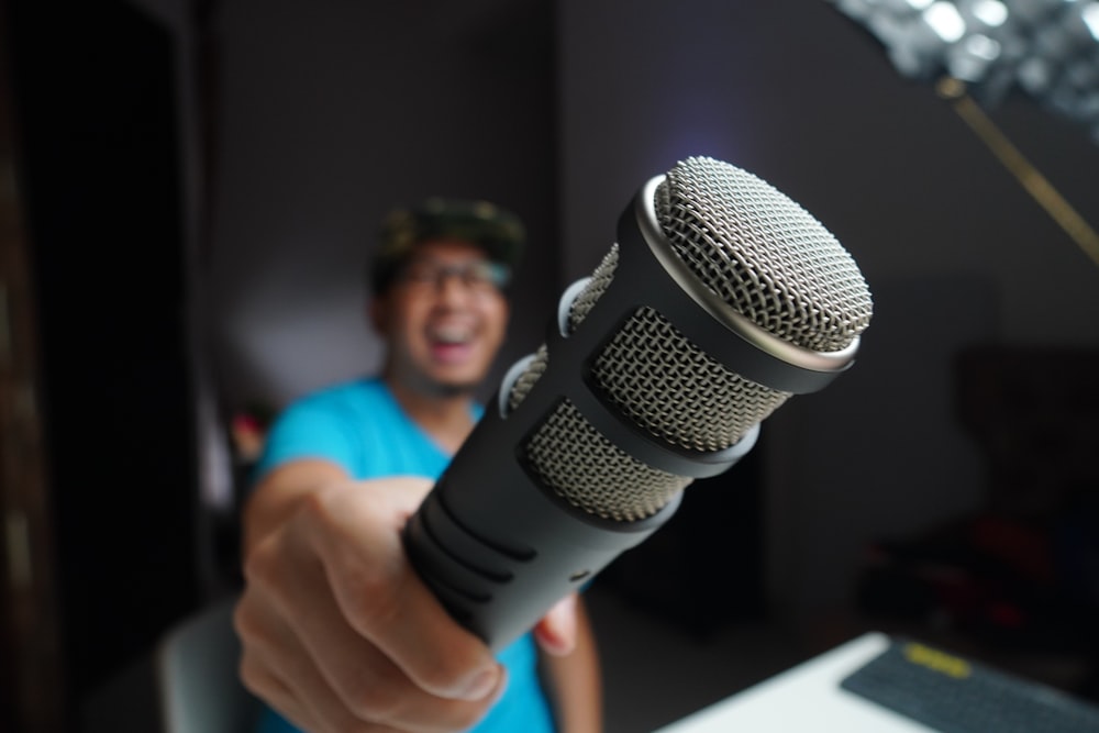 man in blue and black crew neck t-shirt holding microphone