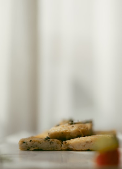 Close-up of a smooth block of silken tofu on a wooden board with fresh herbs around.