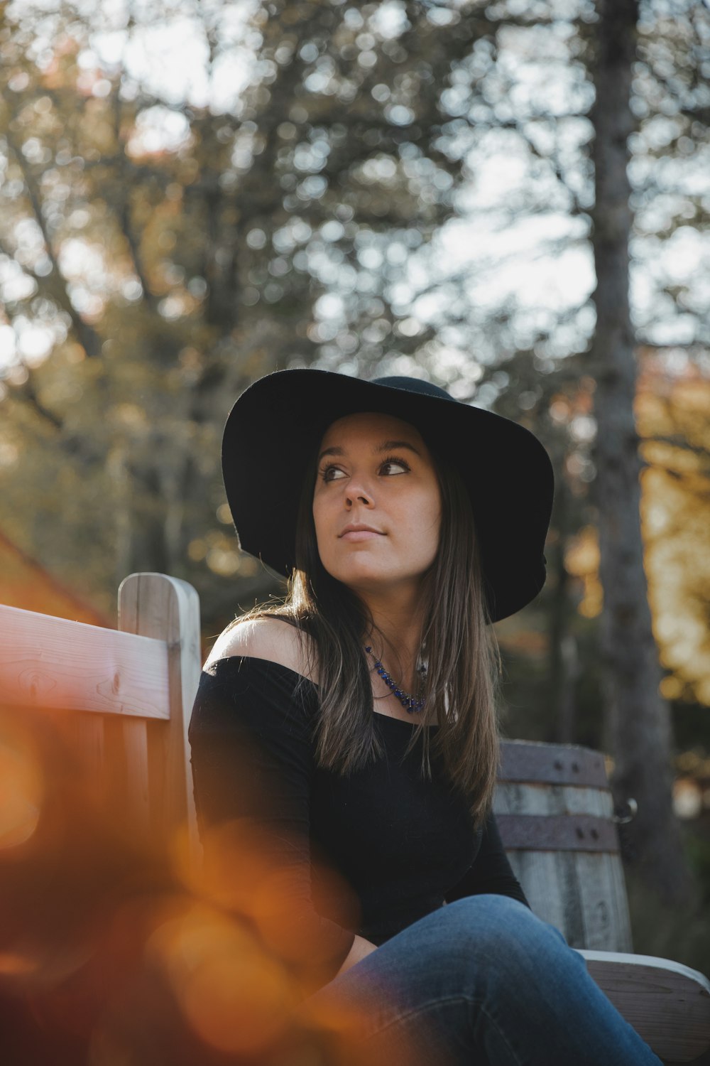 woman in black long sleeve shirt and black hat sitting on bench during daytime