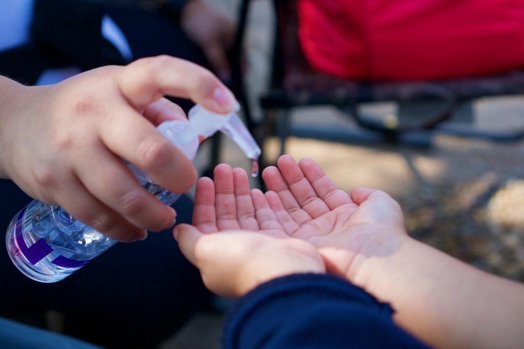 person holding white cigarette stick, cleaning hands with hand sanitizer lotion to kill germs