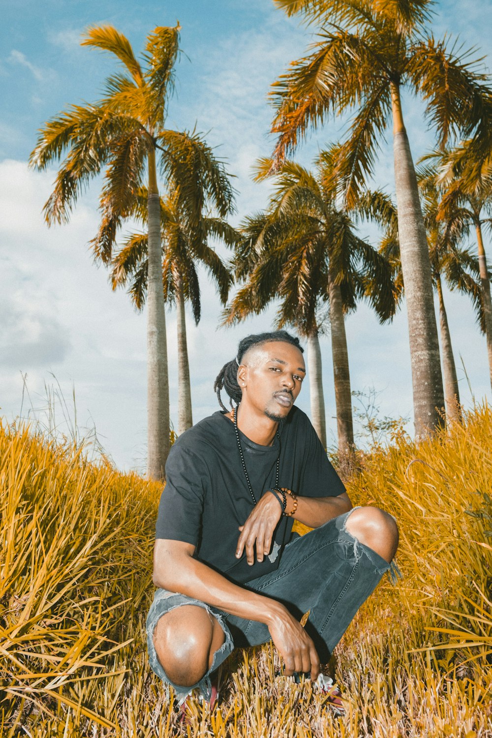 man in black crew neck t-shirt sitting on brown grass during daytime