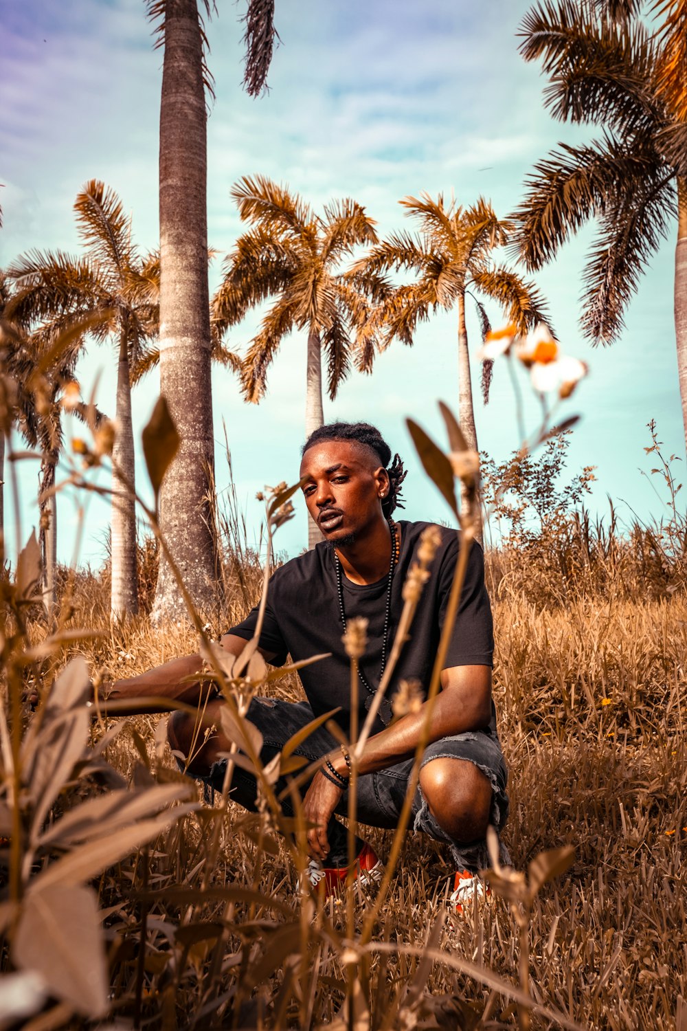 man in black and yellow crew neck t-shirt sitting on brown grass field during daytime