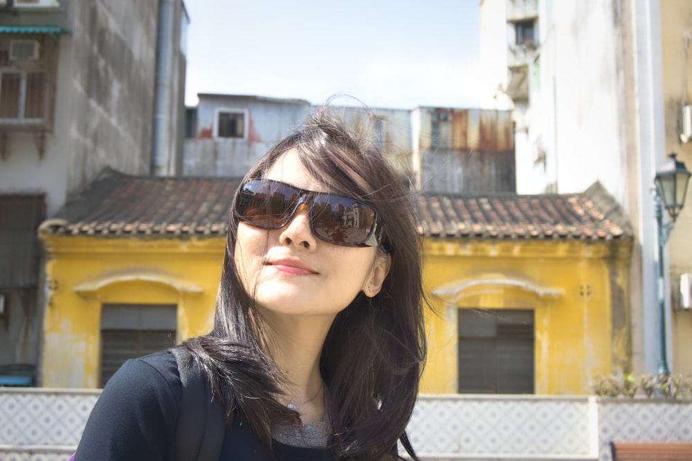 mulher na camisa preta que veste óculos de sol castanhos