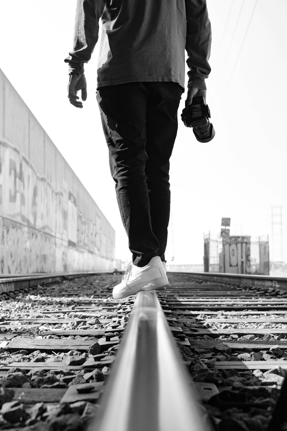 grayscale photo of person in black pants and black leather boots walking on concrete stairs