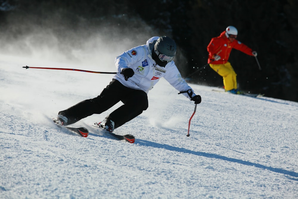 homem em jaqueta vermelha e calças pretas montando lâminas de esqui no chão coberto de neve durante o dia