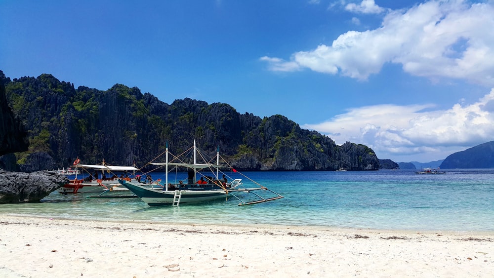 blue and white boat on sea shore during daytime