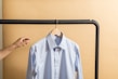 Close-up of a neatly pressed smart casual shirt on a wooden hanger.