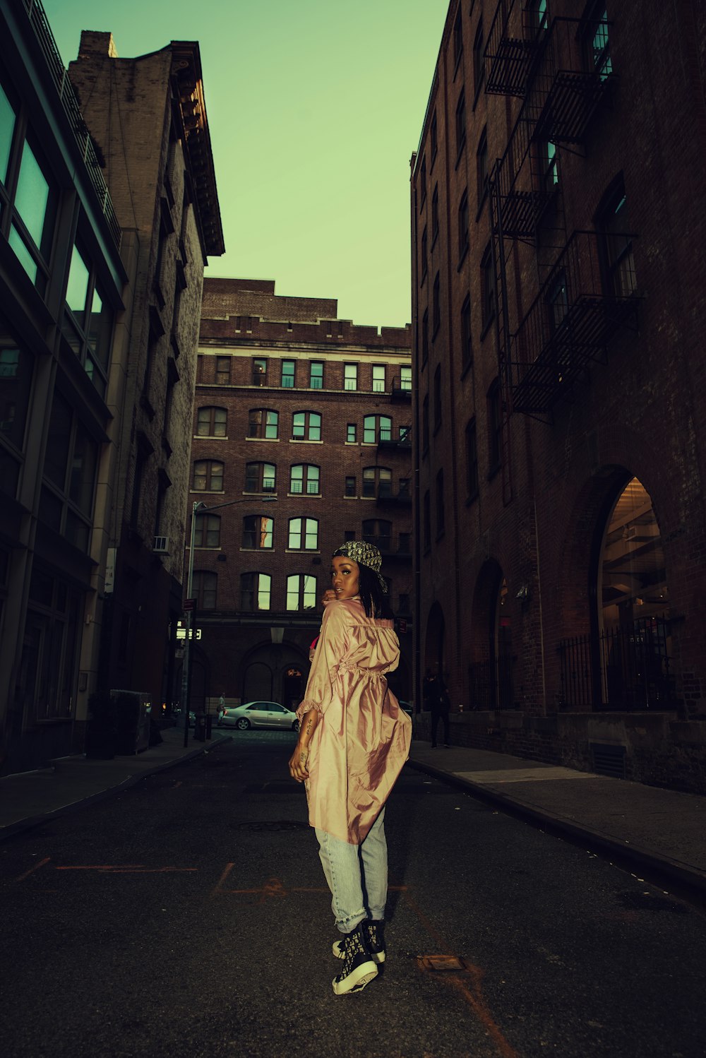 woman in brown coat standing on sidewalk during daytime