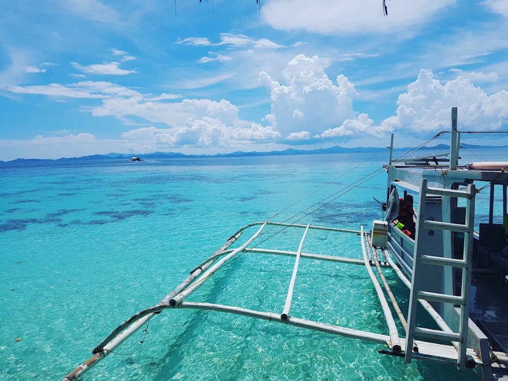 white and blue boat on sea under blue sky during daytime