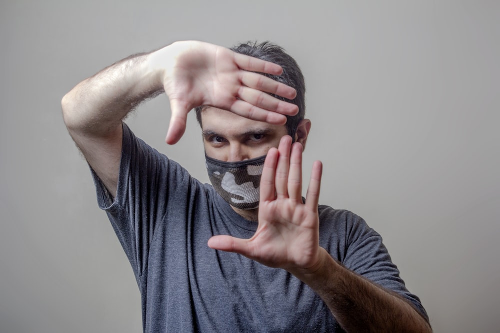 Mann im grauen Rundhals-T-Shirt, das sein Gesicht mit der Hand bedeckt