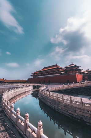 brown and red temple near body of water under blue sky during daytime