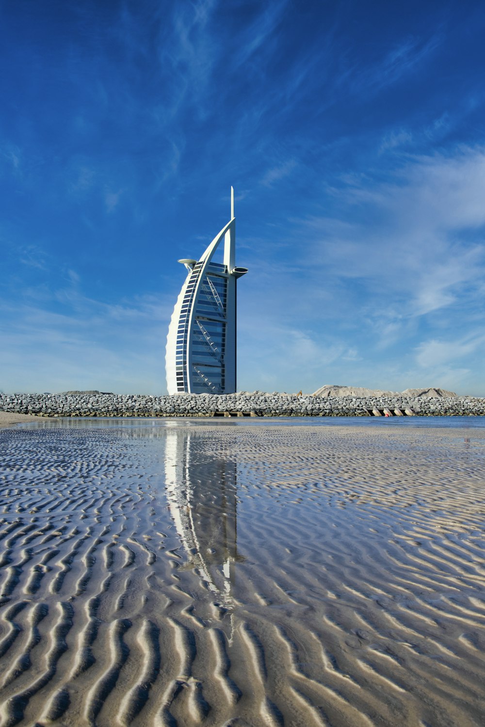 white and blue windmill on brown sand under blue sky during daytime