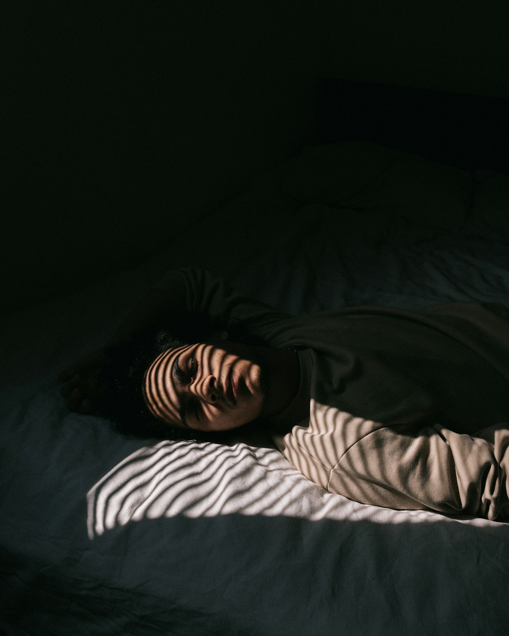 man in black and white striped long sleeve shirt lying on bed