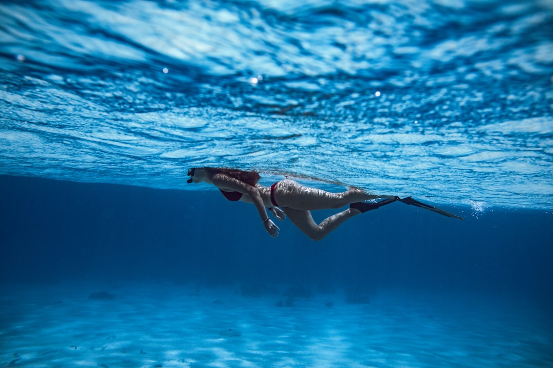 woman in black bikini swimming in water, A freediver-girl snokeling across the sea