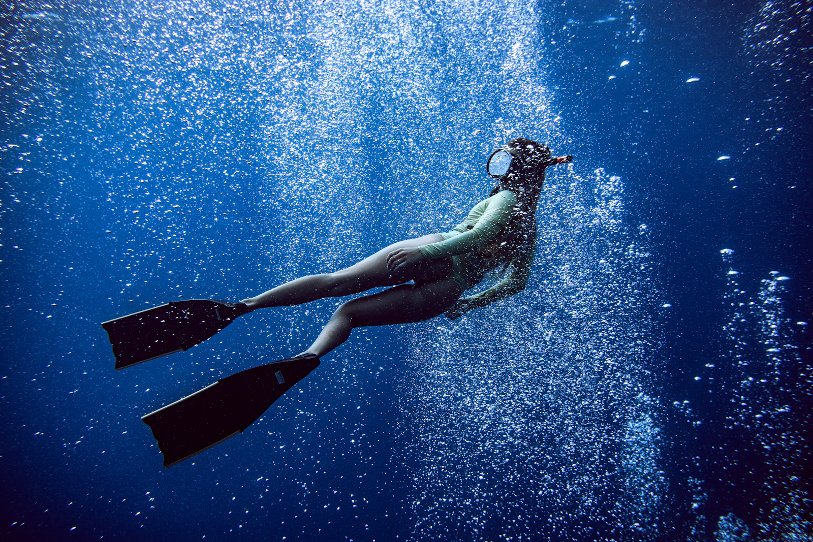 Diver hanging serenely in blue water surrounded by fine bubbles