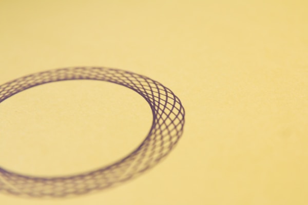 Minimalist medallion with intricate engraving, displayed against a clean, dark neutral background.