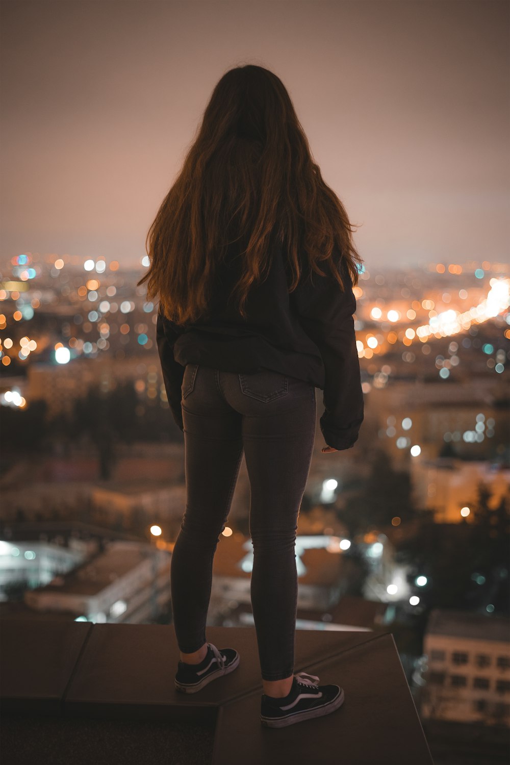 woman in black jacket and black pants standing on the street during night time