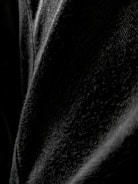 A close-up view of black denim fabric, highlighting the texture and weave of the material with varying shades of black and gray.