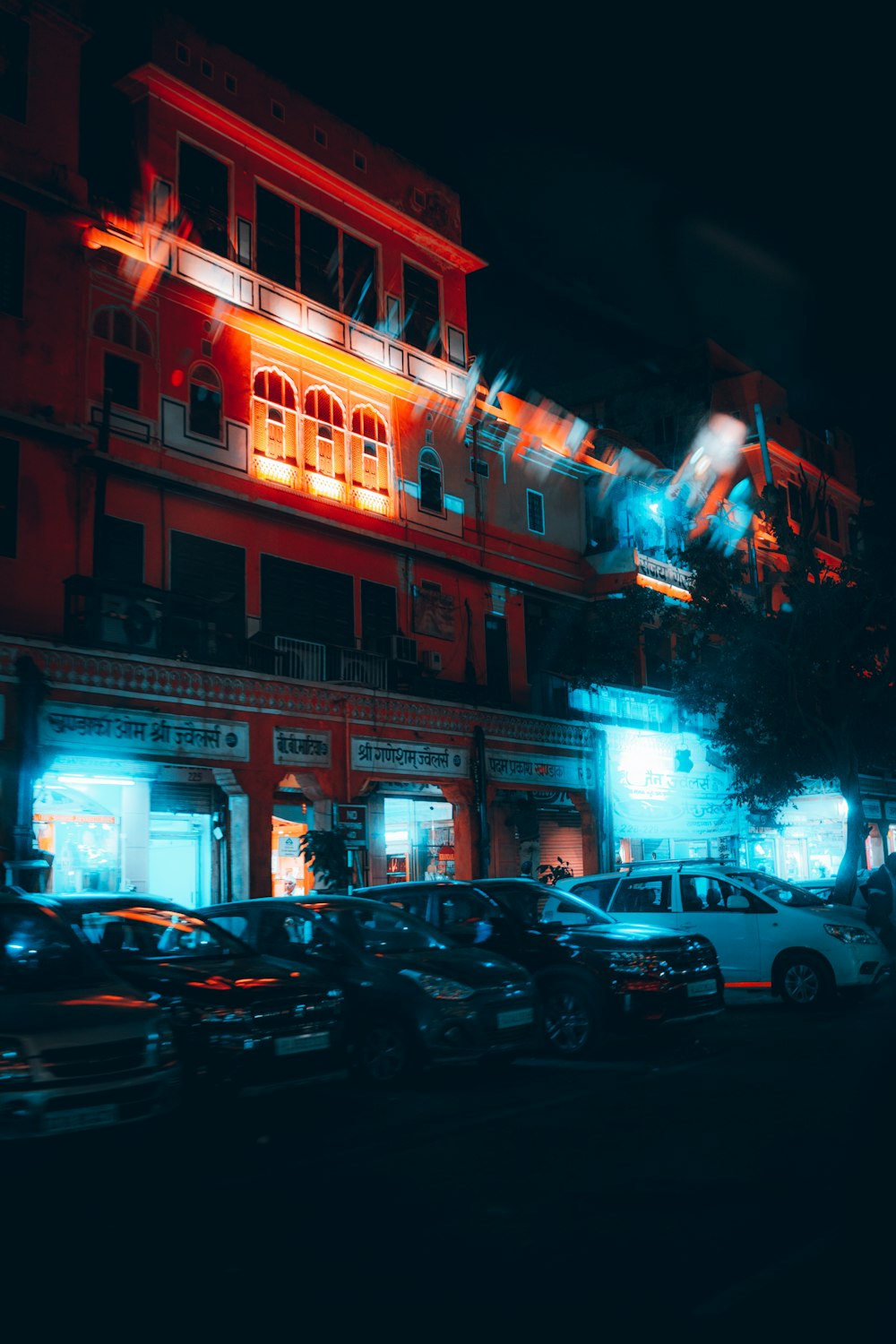 cars parked in front of red building during night time