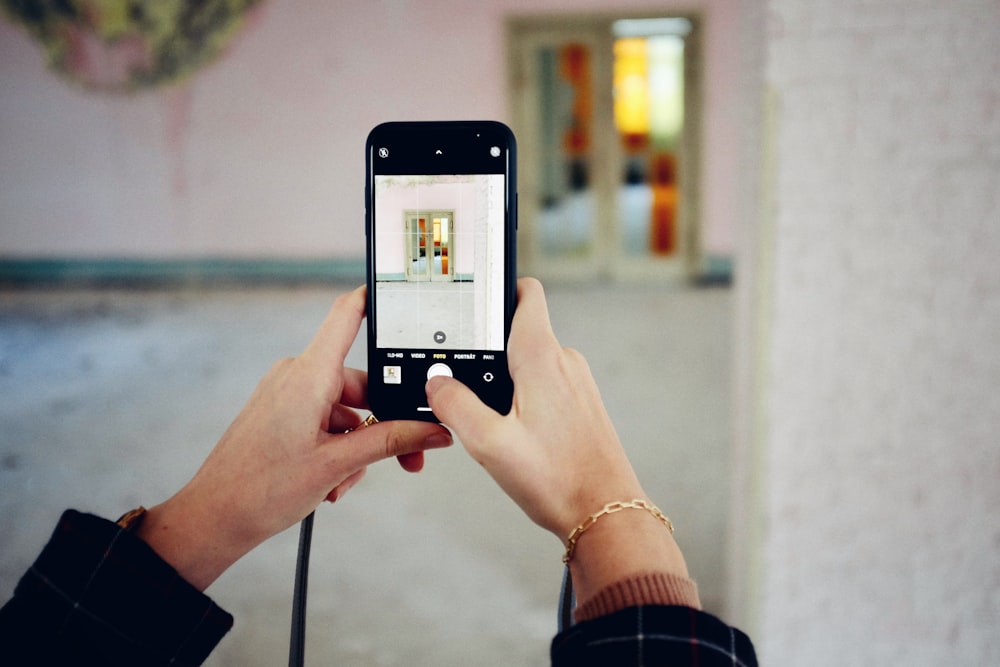 person holding silver iphone 6 taking photo of white building during daytime